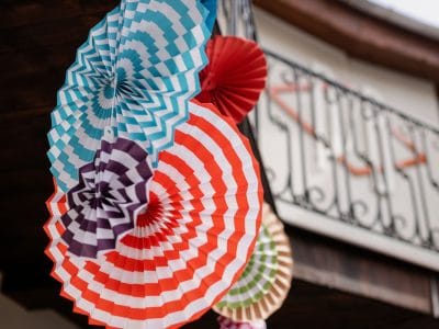 Kleurrijke zelfgemaakte papieren waaiers als feestdecoratie buiten opgehangen