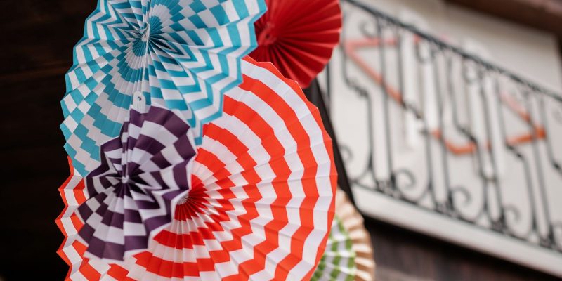 Kleurrijke zelfgemaakte papieren waaiers als feestdecoratie buiten opgehangen
