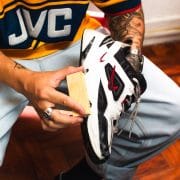Iemand maakt binnen een witte sneaker schoon met schoonmaakspullen op tafel