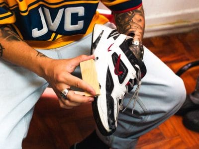 Iemand maakt binnen een witte sneaker schoon met schoonmaakspullen op tafel